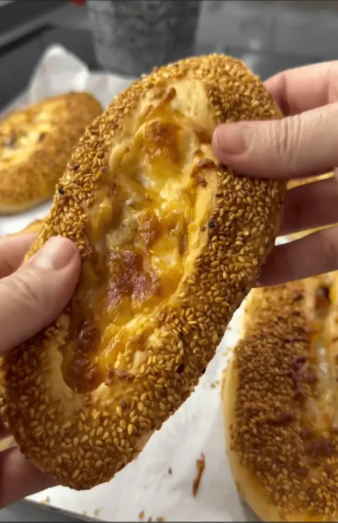Freshly baked bagel buns with cheese and sausage topped with sesame seeds