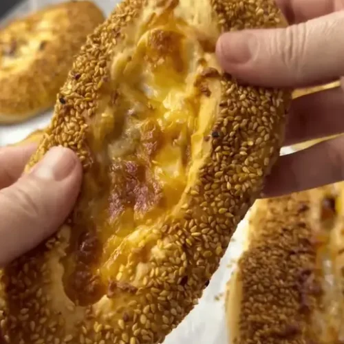 Freshly baked bagel buns with cheese and sausage topped with sesame seeds