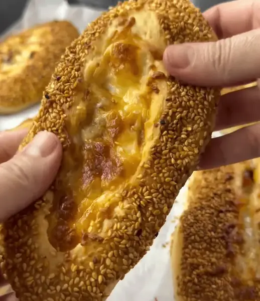 Freshly baked bagel buns with cheese and sausage topped with sesame seeds