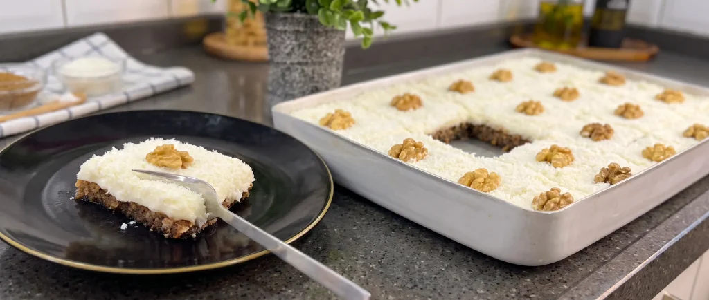 Slice of Cyprus Dessert made with walnut syrup cake, topped with smooth custard and sprinkled coconut