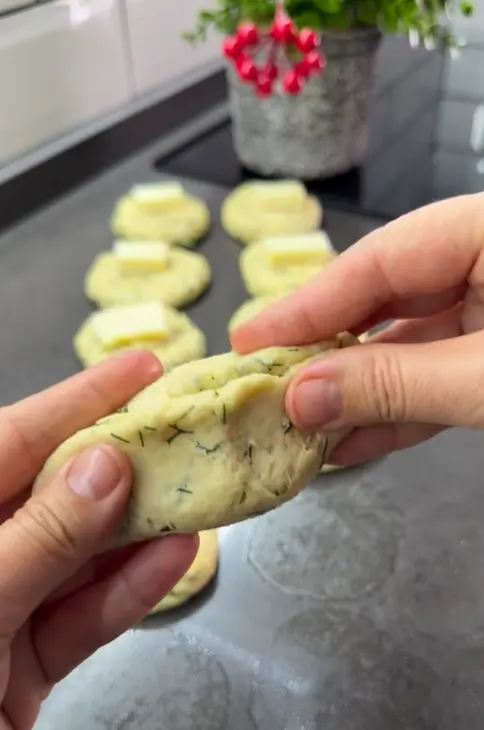A torn open dill and cheese bun showing the soft fluffy texture and melted cheese center.