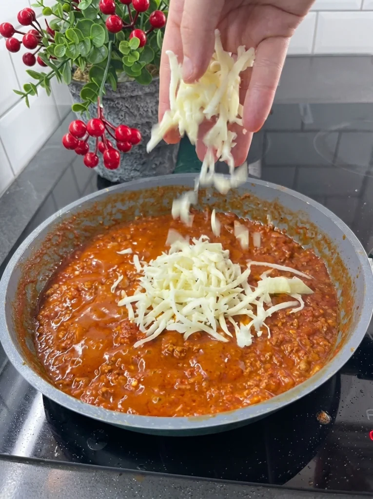 Grated cheddar cheese melting into spaghetti and minced meat sauce