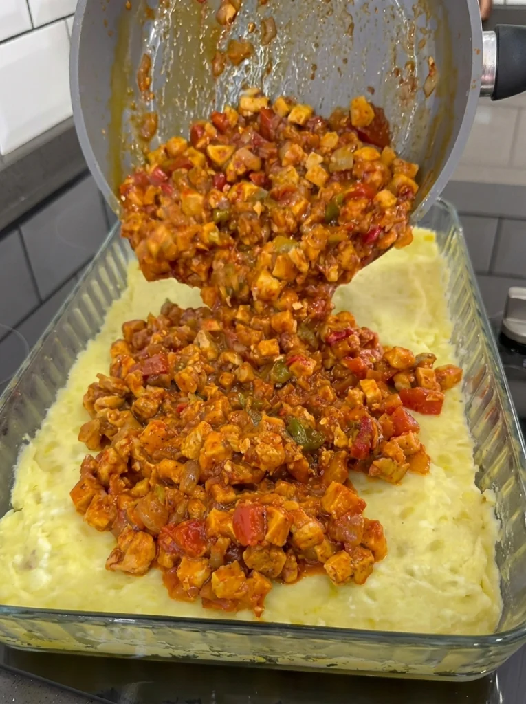 Layers of mashed potatoes, chicken saute, and béchamel sauce before baking