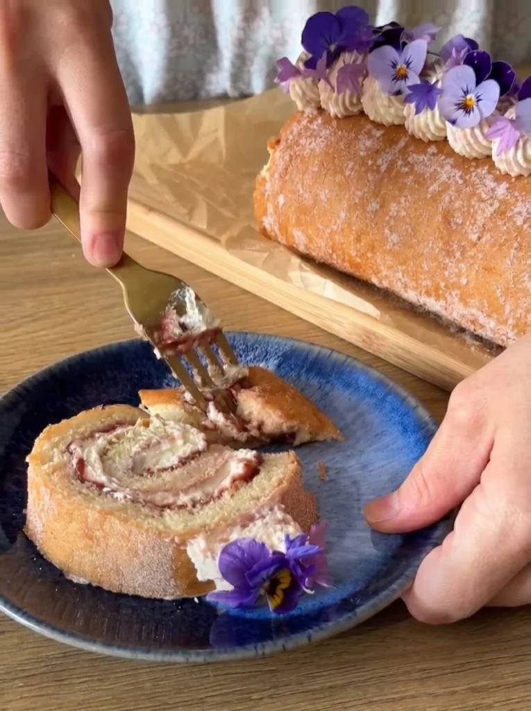 Best Swiss roll recipe topped with powdered sugar and served sliced