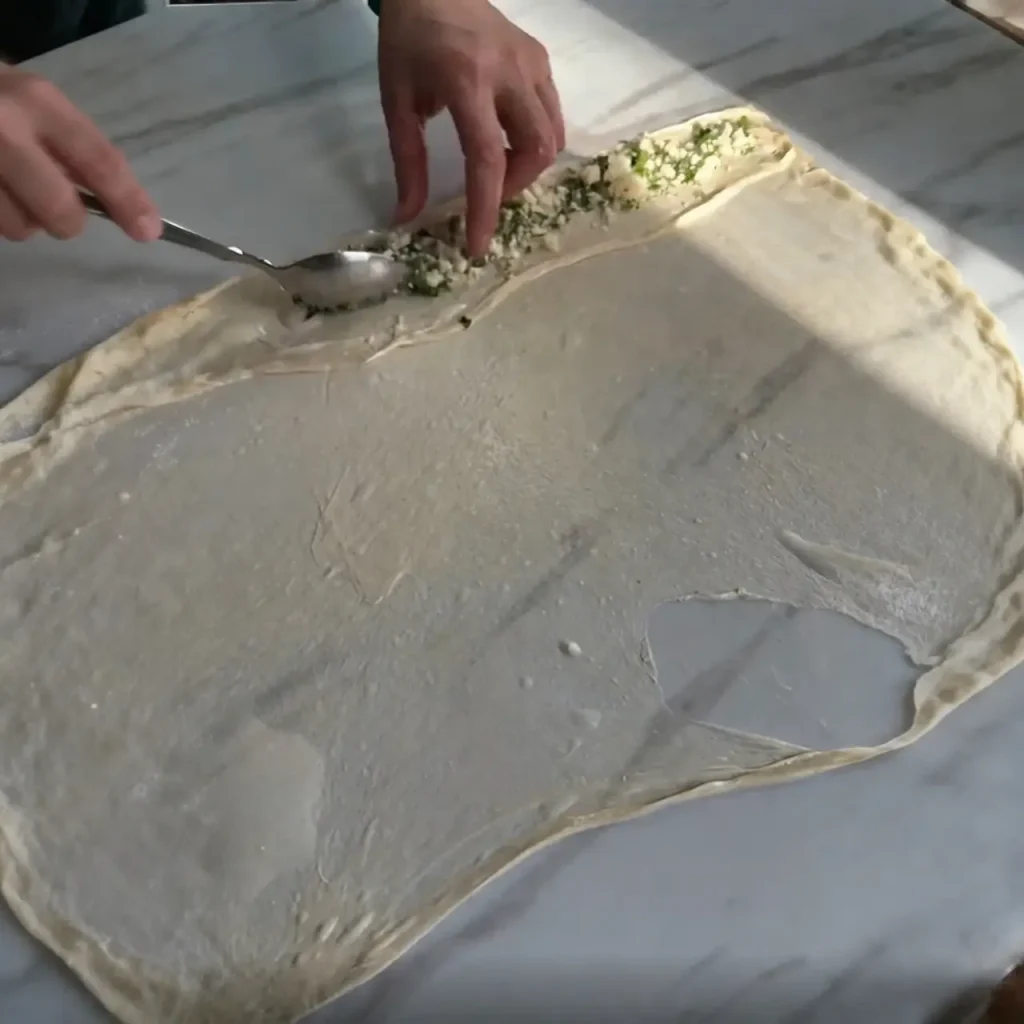White cheese and chopped parsley filling on rolled flatbread dough