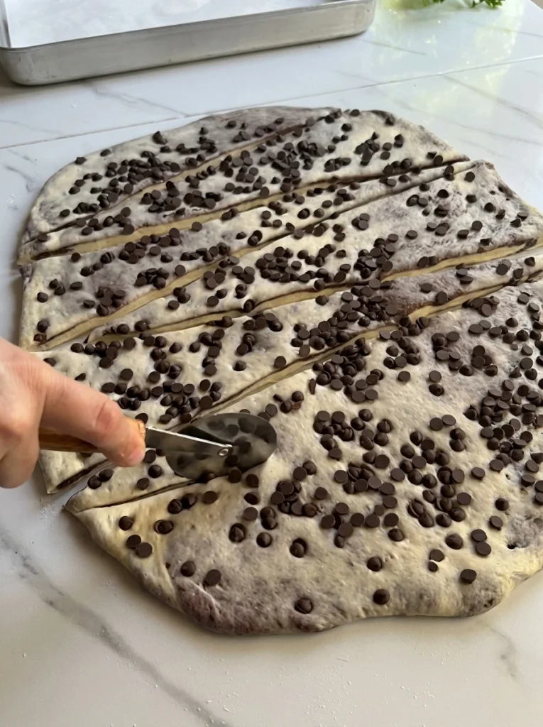 Rolling chocolate croissant rolls into shape before baking