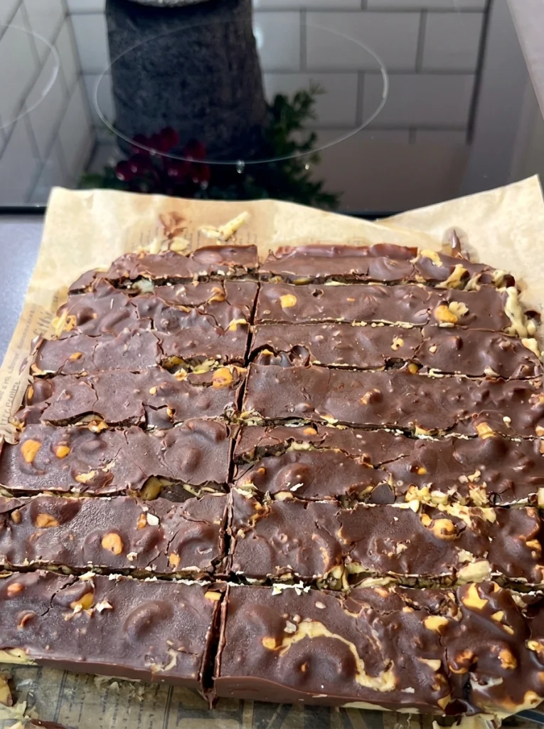 Pouring melted chocolate over peanut butter and dates to make chocolate date bars