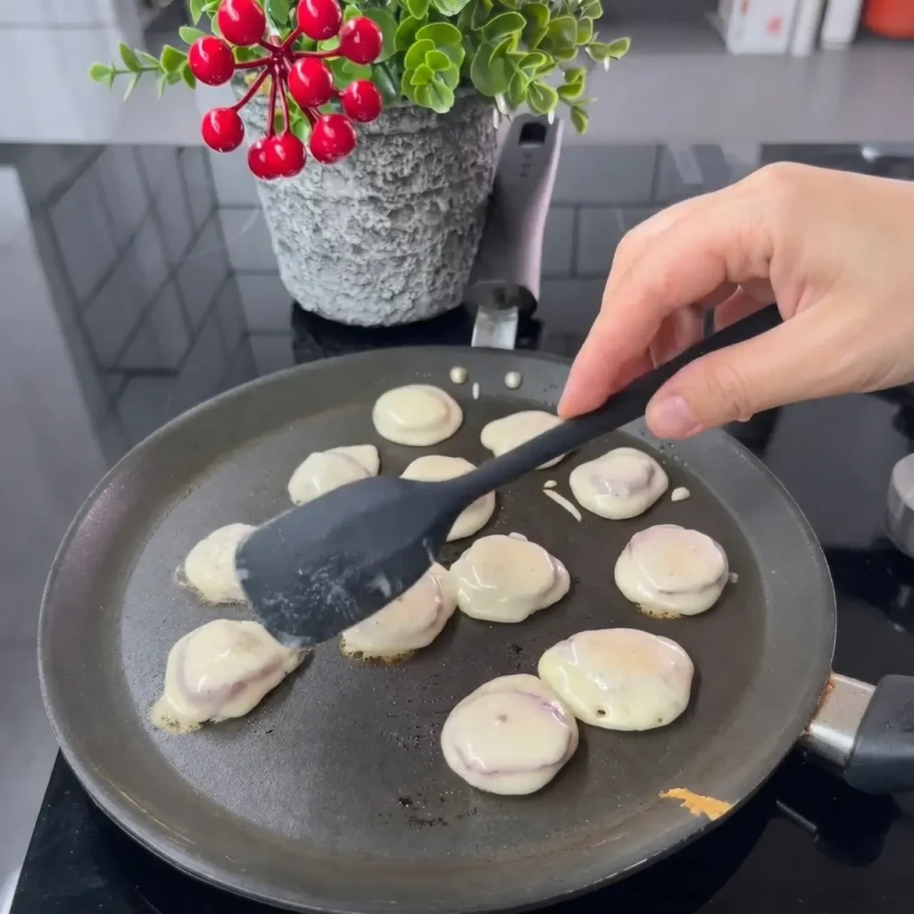 Small mini pancakes cooking in non-stick pan