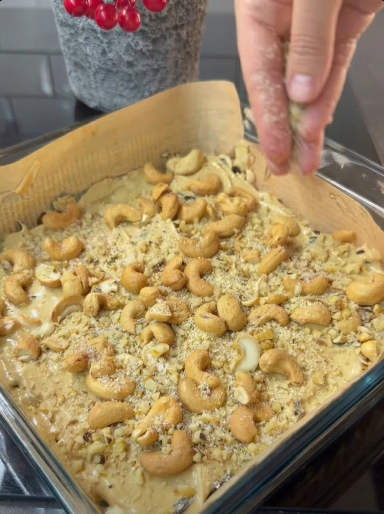 Sprinkling chopped cashews and walnuts over peanut butter layer for chocolate date bars
