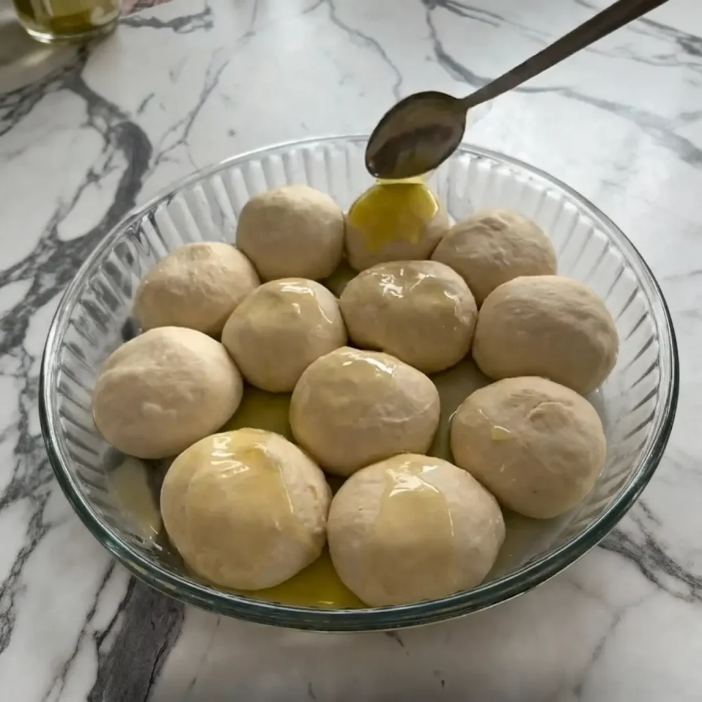 Dough balls resting in oiled tray for layered cheese pastry