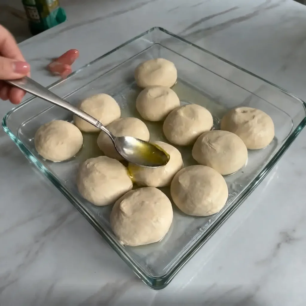Flatbread dough balls resting in butter and oil mixture