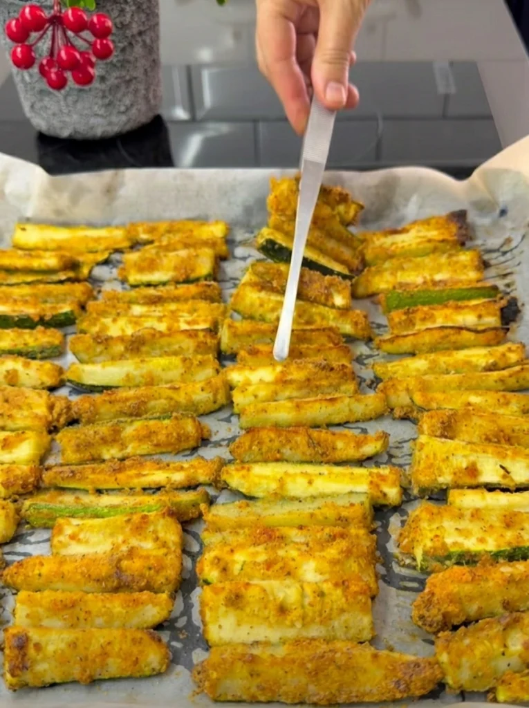 Golden crispy baked zucchini coming out of the oven on a baking tray