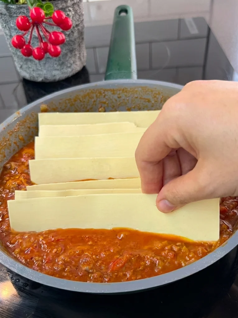 Tomatoes, peppers, and minced meat cooking together in a pan for one-pan lasagna sauce