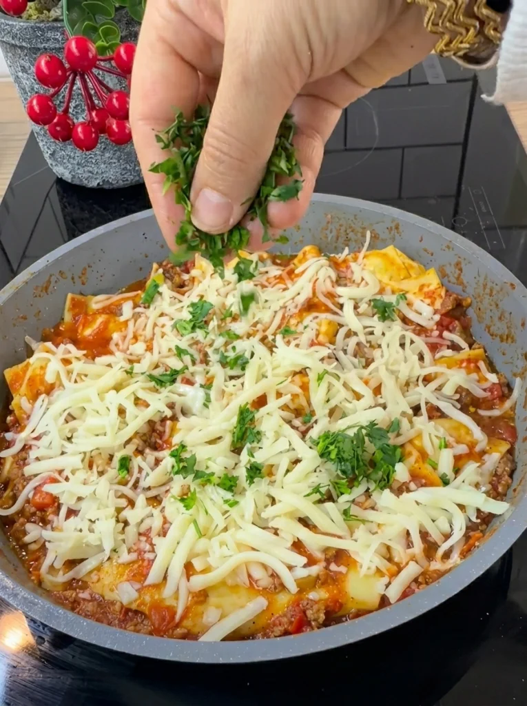 Lasagna sheets layered over tomato sauce in a skillet, cooking without an oven