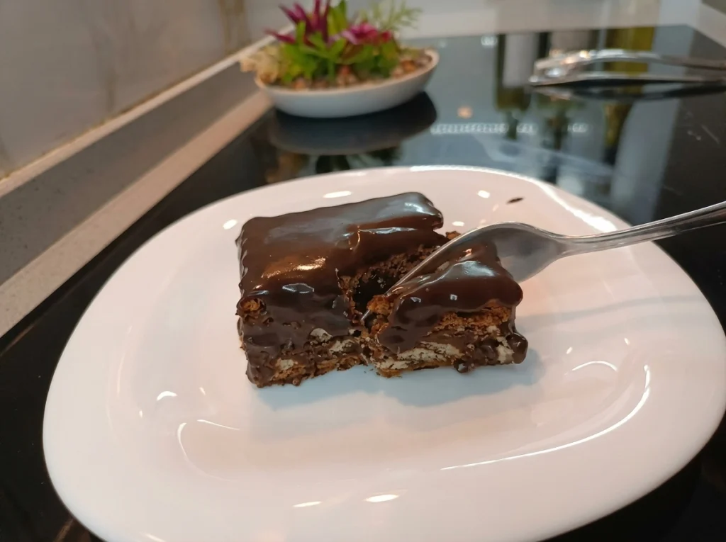 No-bake biscuit cake (Mosaic Cake) sliced on a plate showing chocolate ganache topping