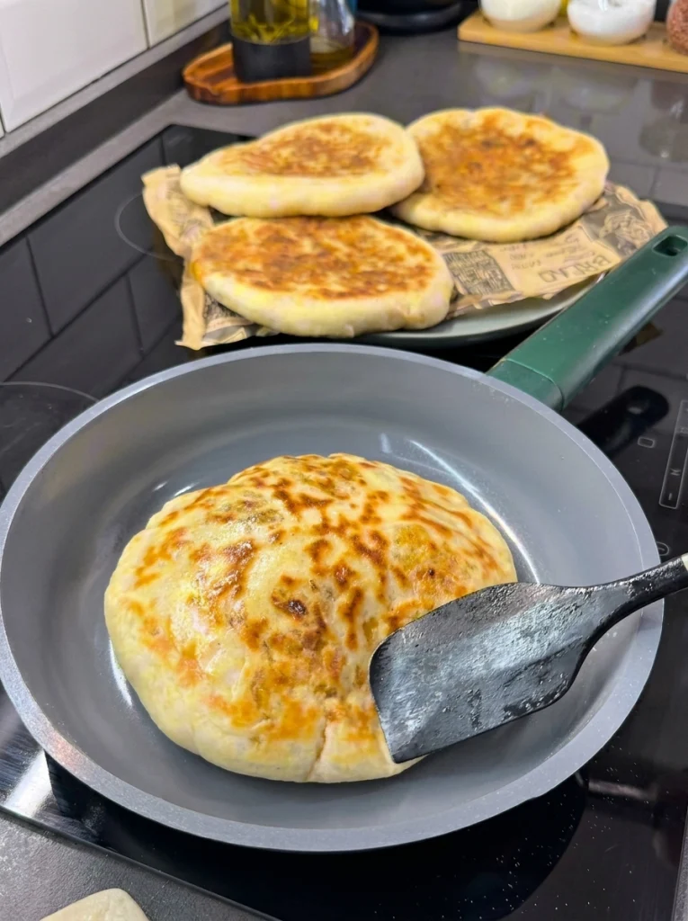 Stuffed pita cooking golden brown on a lightly greased pan