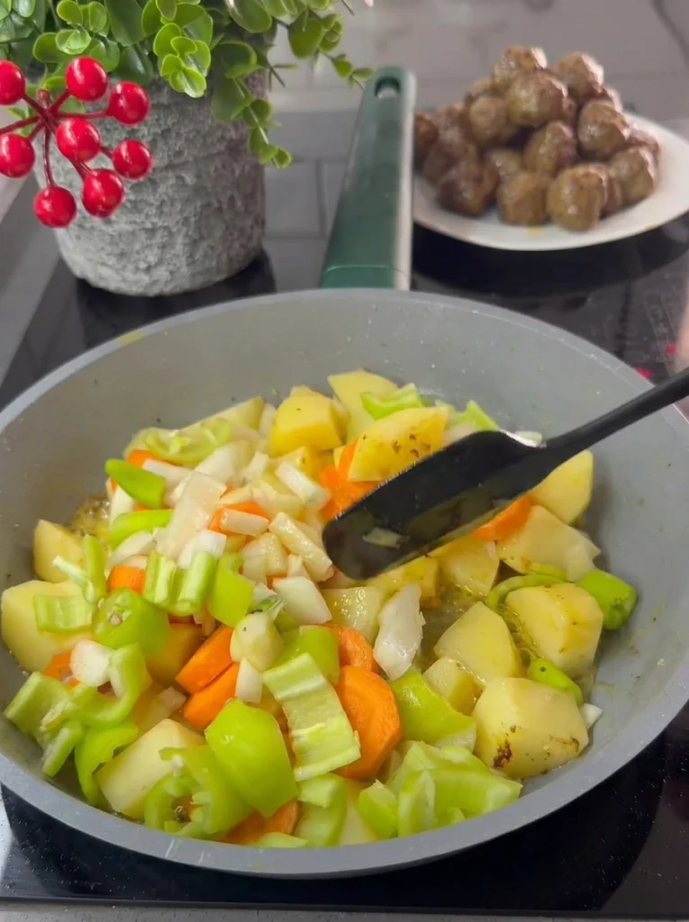 Potatoes, carrots, and bell pepper sautéing in butter in a pot