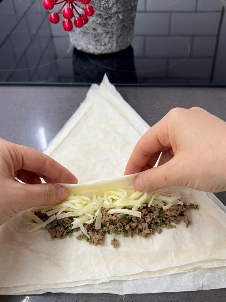 Rolling yufka triangle with minced meat and cheddar cheese filling