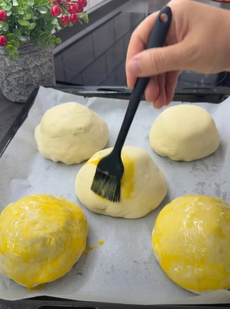 Stuffed cheeseburger buns brushed with egg yolk and sprinkled with sesame seeds