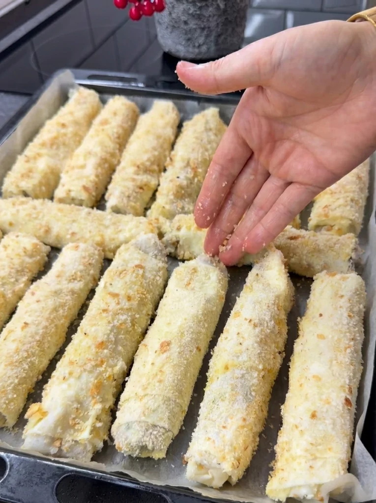 Uncooked crispy pastry rolls arranged on a baking tray