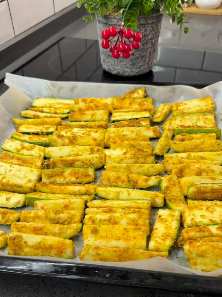 Seasoned zucchini slices arranged on a baking tray lined with parchment paper