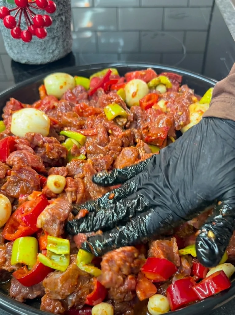 Mixing beef and vegetables in a tray for Belen Tava