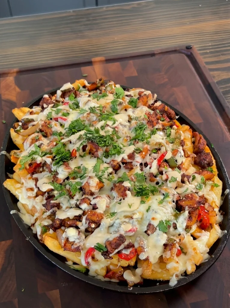 Close-up of a cheesy bite of chicken fajita loaded fries with melted cheese pull