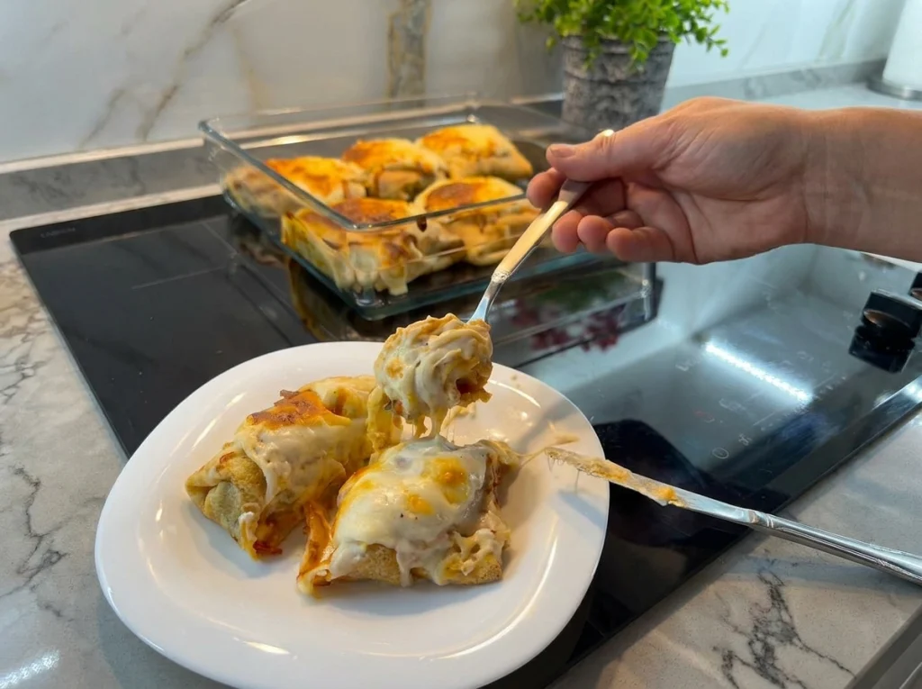 Baked chicken crepe rolls topped with béchamel sauce and melted cheese