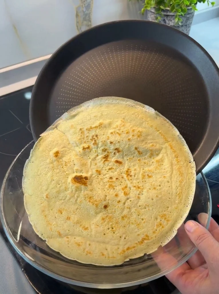Thin homemade crepes cooking on a non-stick pan