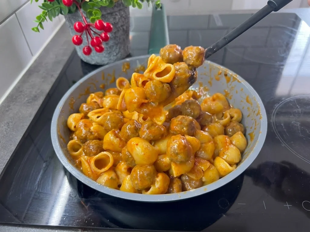 One-pot meatball pasta with tomato sauce and melted cheddar cheese