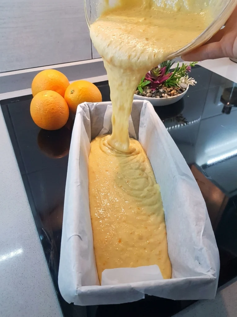 Orange cake batter poured into a loaf pan before baking