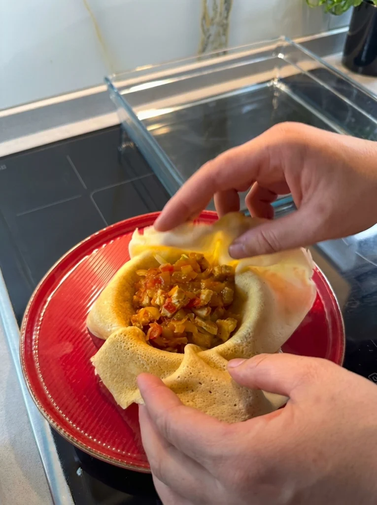 Chicken filling being rolled inside a crepe