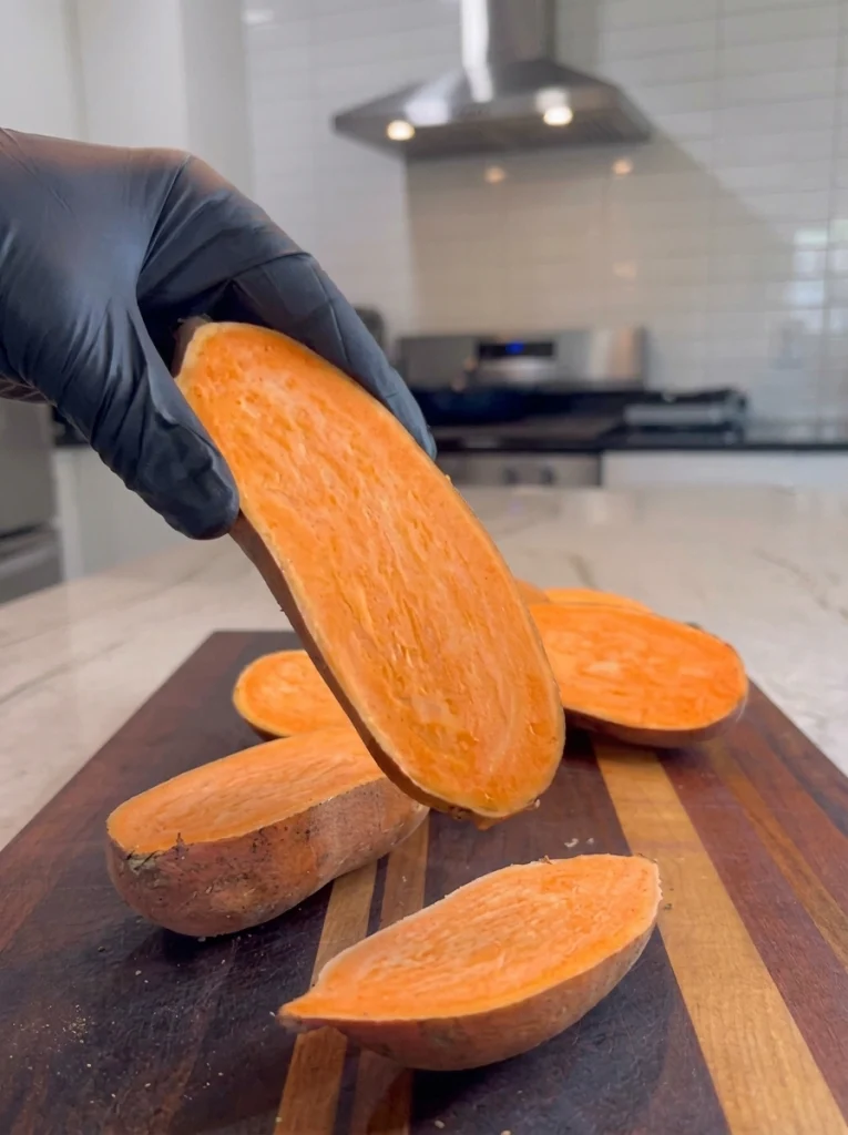 Sweet potatoes sliced in half lengthwise on a cutting board