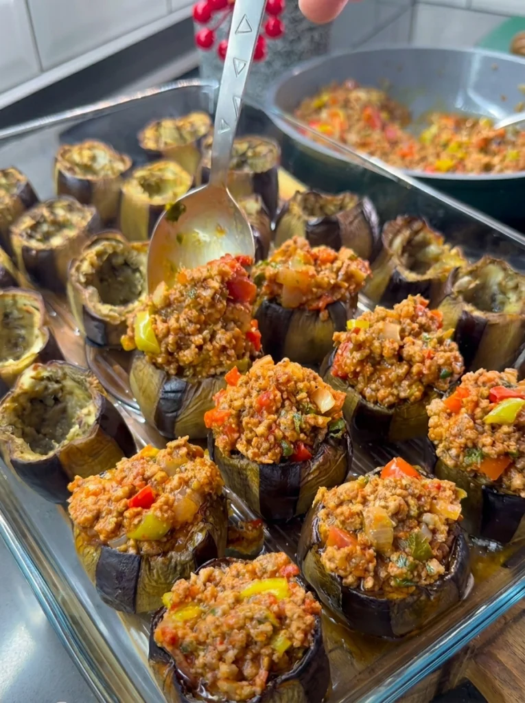 Eggplants stuffed with meat filling and topped with tomato slices before final bake