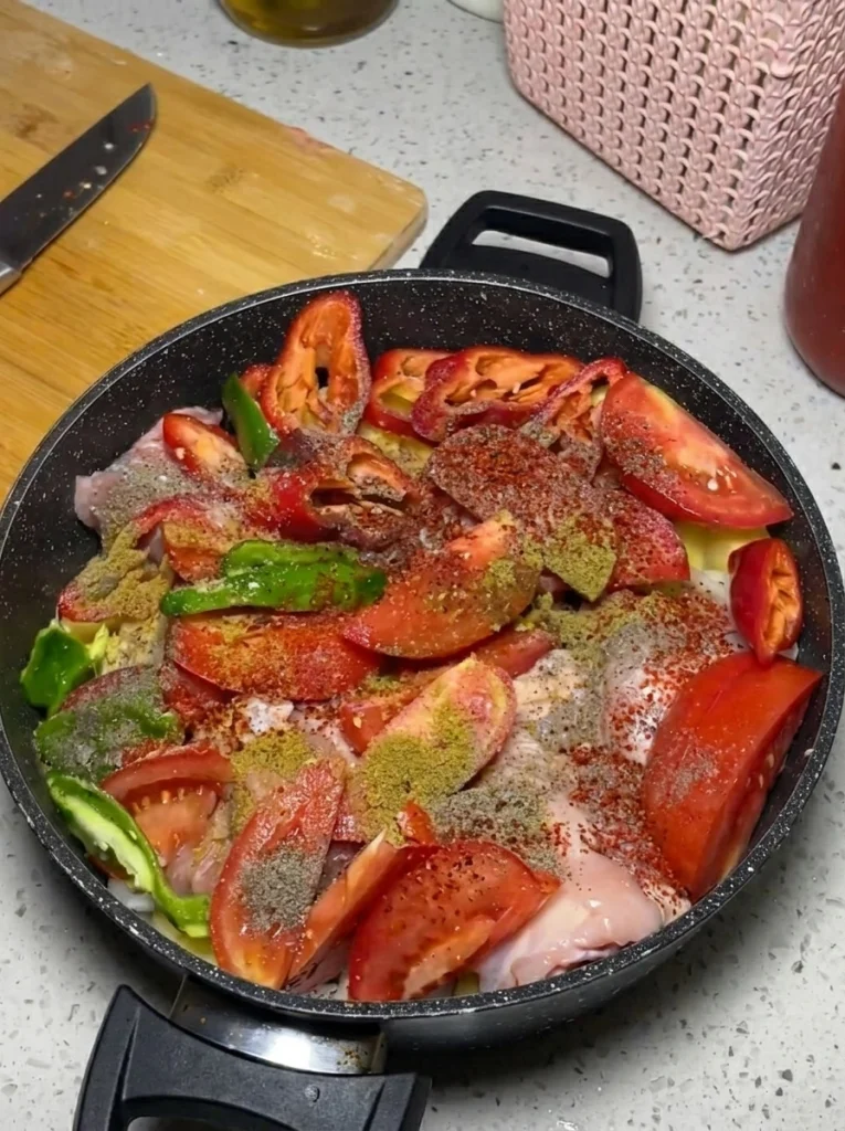 Tavuklu Patates Tavası simmering on the stovetop with tomato sauce